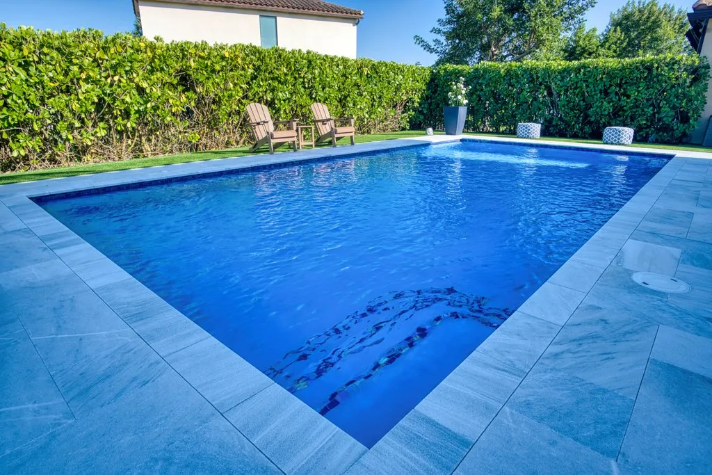 Rectangular pool with glass tile waterline and marble deck in Royal Palm Beach