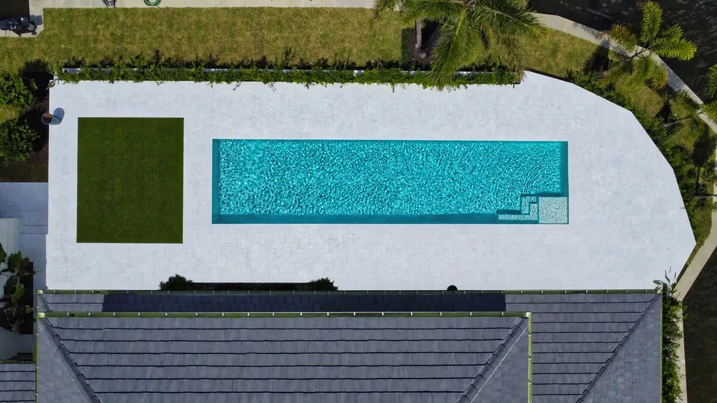 Top-down drone view of pool, marble deck and turf, custom pool builder in North Palm Beach, FL